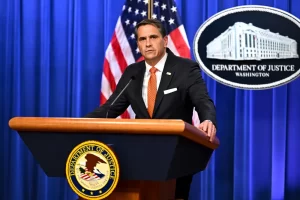 Acting Attorney General Todd Blanche speaks at a Department of Justice podium with U.S. flags and the DOJ seal in the background.